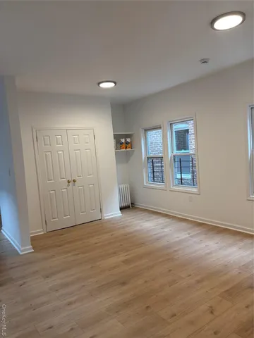a view of an empty room with window and wooden floor