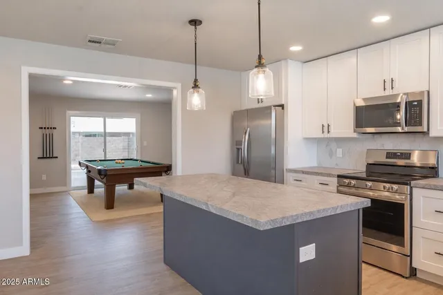 a kitchen with stainless steel appliances granite countertop a stove a refrigerator a oven a sink a dining table and chairs