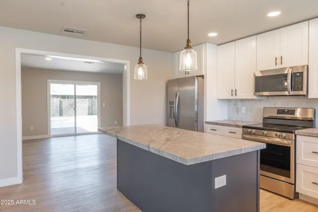 a kitchen with stainless steel appliances granite countertop a refrigerator a sink a stove and a wooden floors