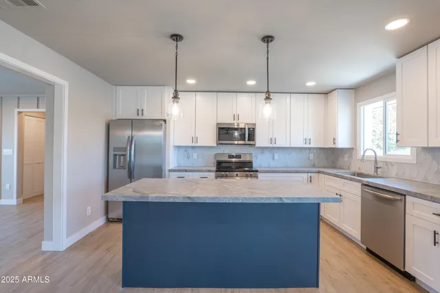 a large kitchen with stainless steel appliances granite countertop a sink a stove a refrigerator and island