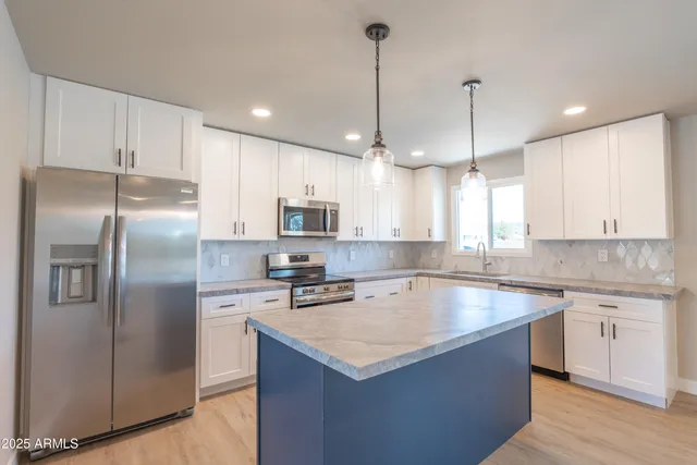 a kitchen with stainless steel appliances granite countertop a sink a stove a refrigerator a center island and cabinets