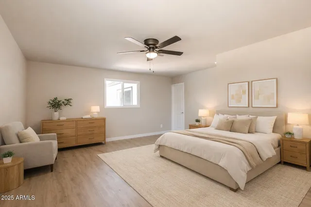 a bedroom with a bed couches chair and a potted plant with wooden floor