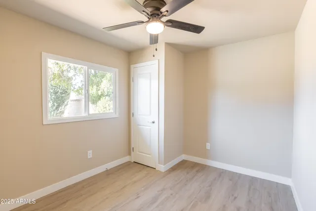 an empty room with a window and a fan