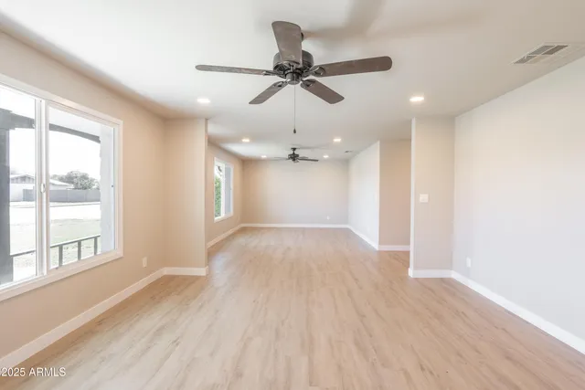 a view of an empty room with a window and wooden floor