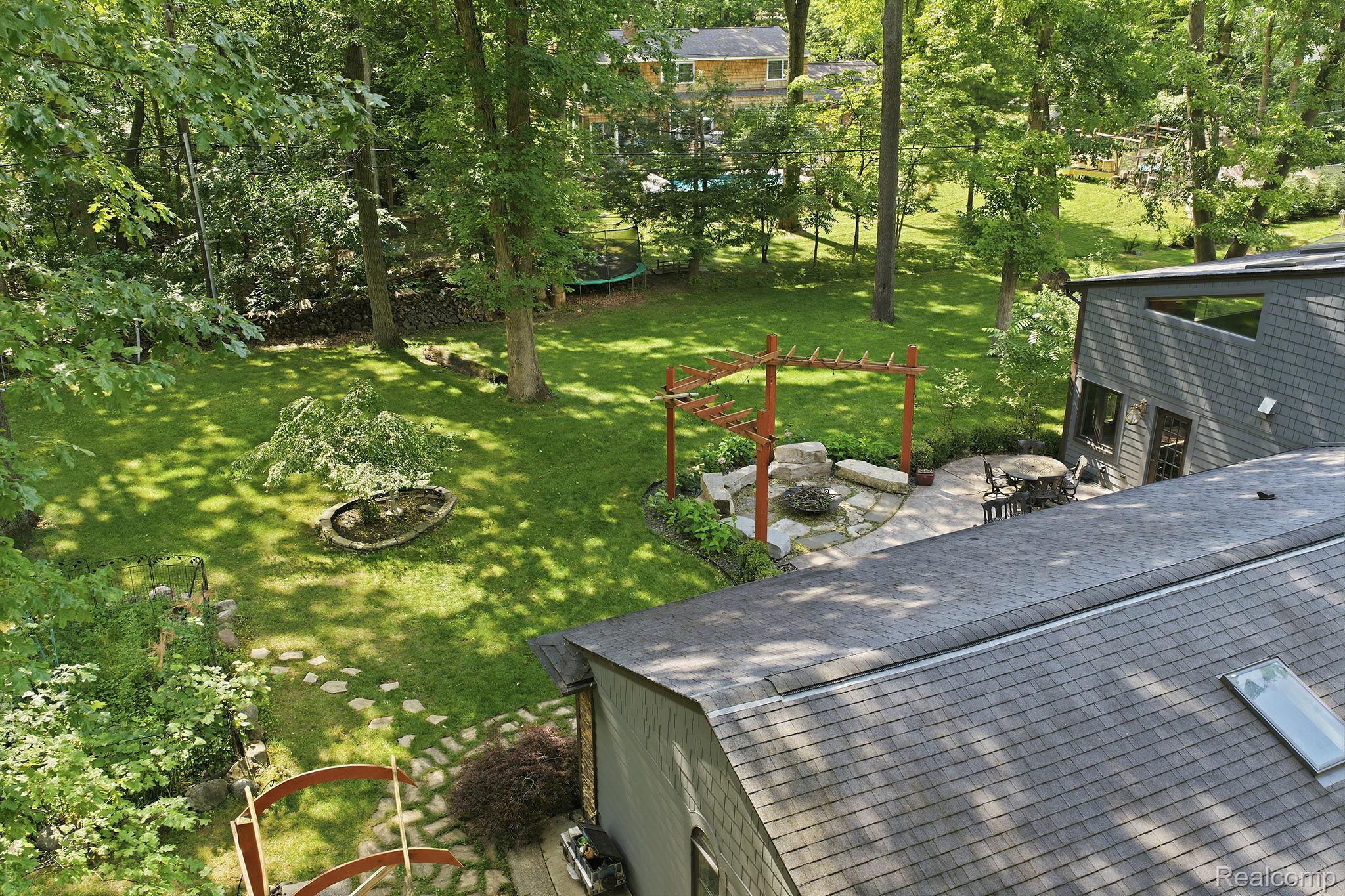 1258 Priscilla Lane Rochester, MI 48309 - Photo 12 of 56 Expansive backyard featuring a manicured lawn, stone patio, and a pergola with a fire pit area