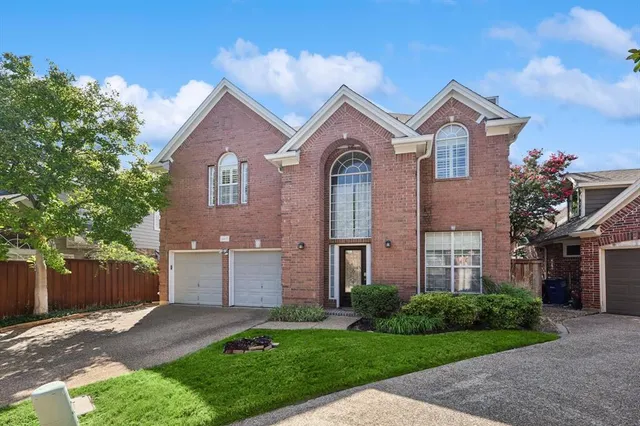 a view of a brick house next to a yard with large trees