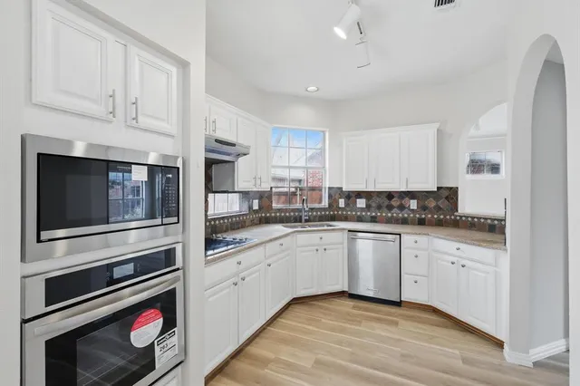 a kitchen with stainless steel appliances granite countertop a stove and white cabinets