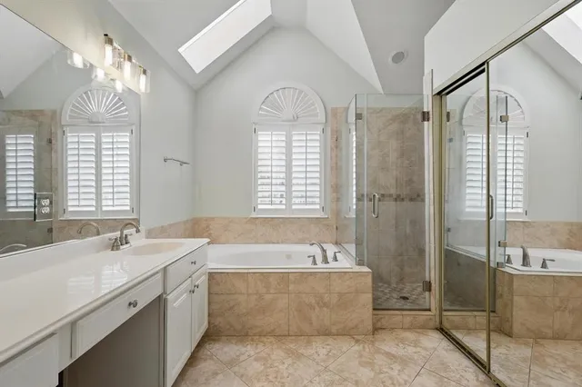 a bathroom with a double vanity sink bathtub and next to a window