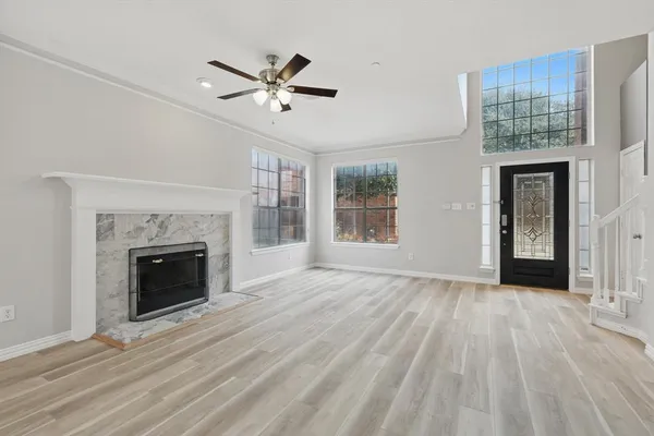 a view of an empty room with wooden floor fireplace and a window