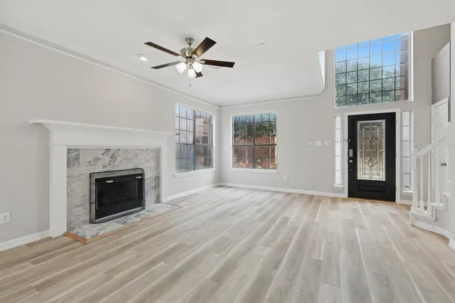 a view of an empty room with wooden floor fireplace and a window