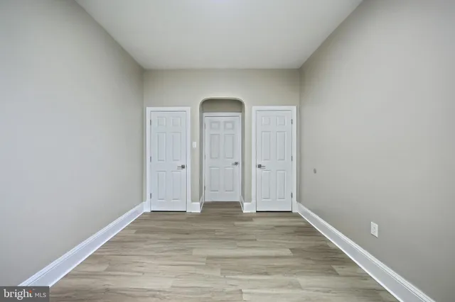 a view of an empty room with wooden floor and window