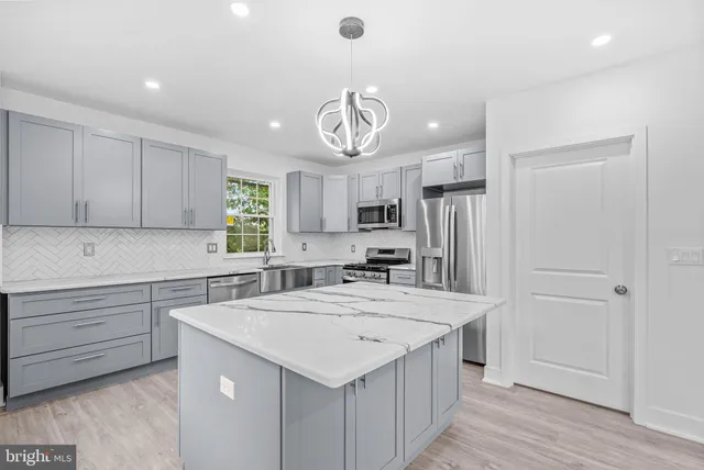a kitchen with a sink a center island cabinets and stainless steel appliances