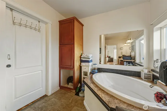 a bathroom with a tub a sink and a large mirror