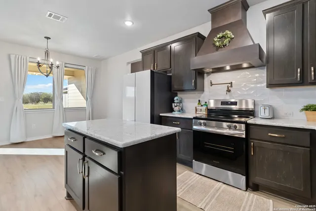 a kitchen with stainless steel appliances granite countertop a stove a refrigerator and a sink