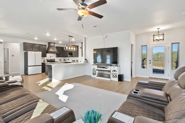 a living room with stainless steel appliances furniture and a flat screen tv