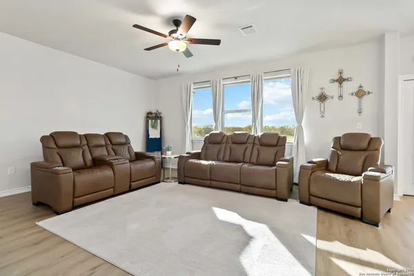 a living room with furniture a ceiling fan a lamp and a window