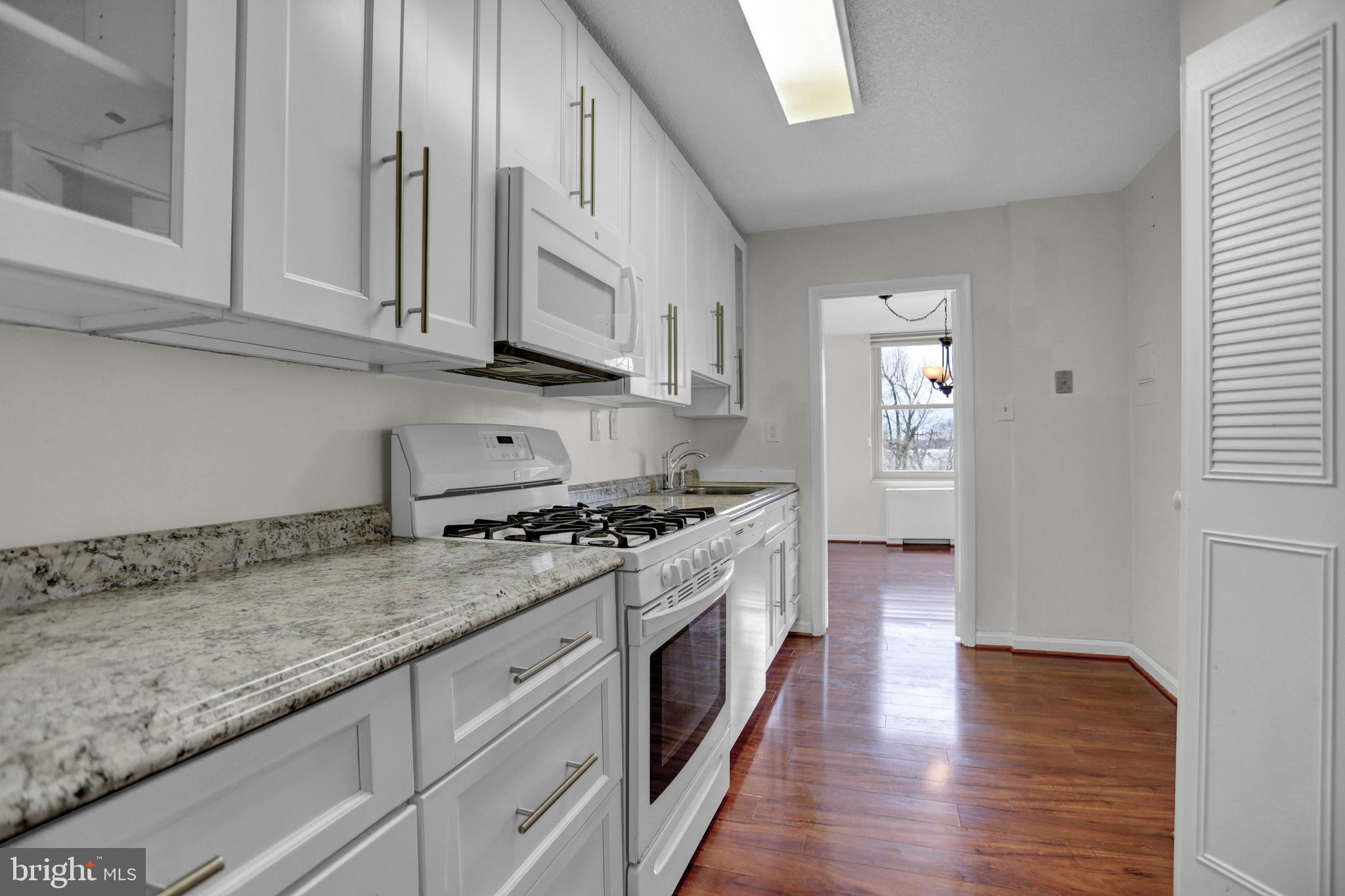 4401 Roland Avenue, Unit 304 Baltimore, MD 21210 - Photo 12 of 50 a kitchen with stainless steel appliances granite countertop a stove a sink and a white refrigerator with white cabinets
