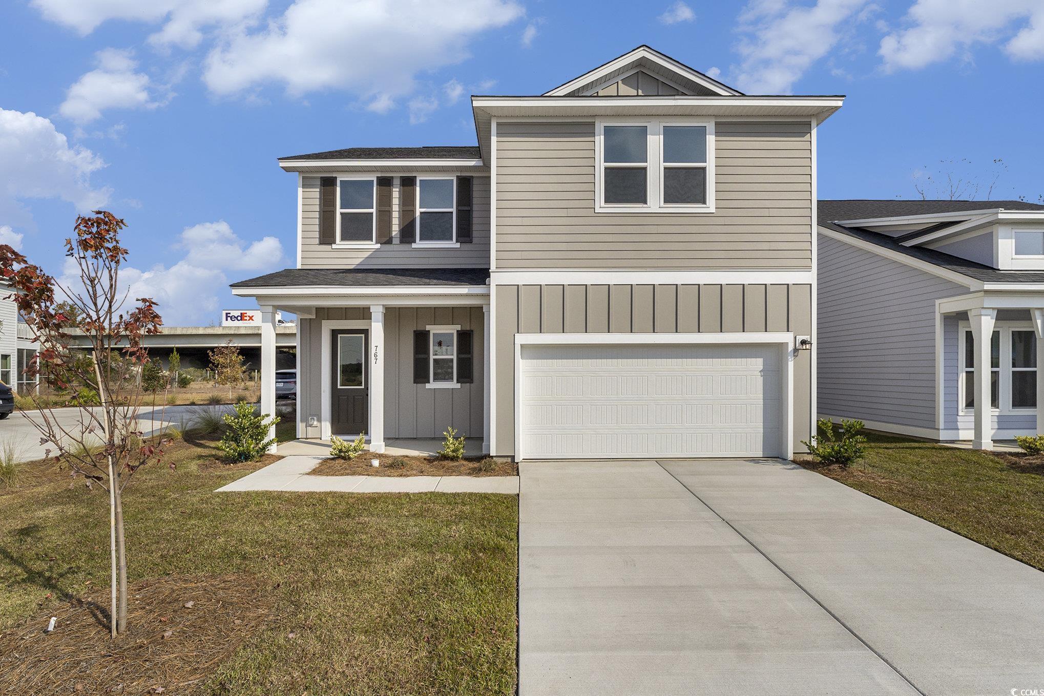View of front of property with board and batten siding, a front yard, a porch, concrete driveway, and an attached garage