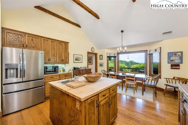 a kitchen with a refrigerator a stove and a dining table with wooden floor