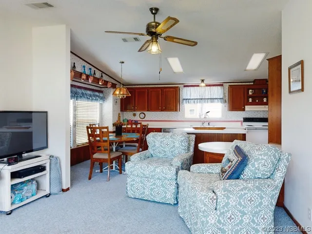 a living room with furniture kitchen view and a flat screen tv