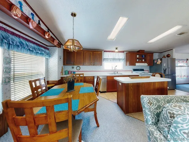 a kitchen with stainless steel appliances granite countertop a kitchen island a stove a sink a dining table and chairs