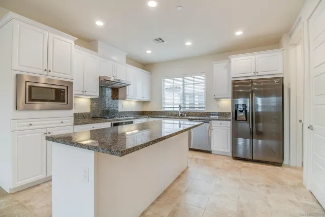 a kitchen with kitchen island granite countertop a sink stainless steel appliances and white cabinets