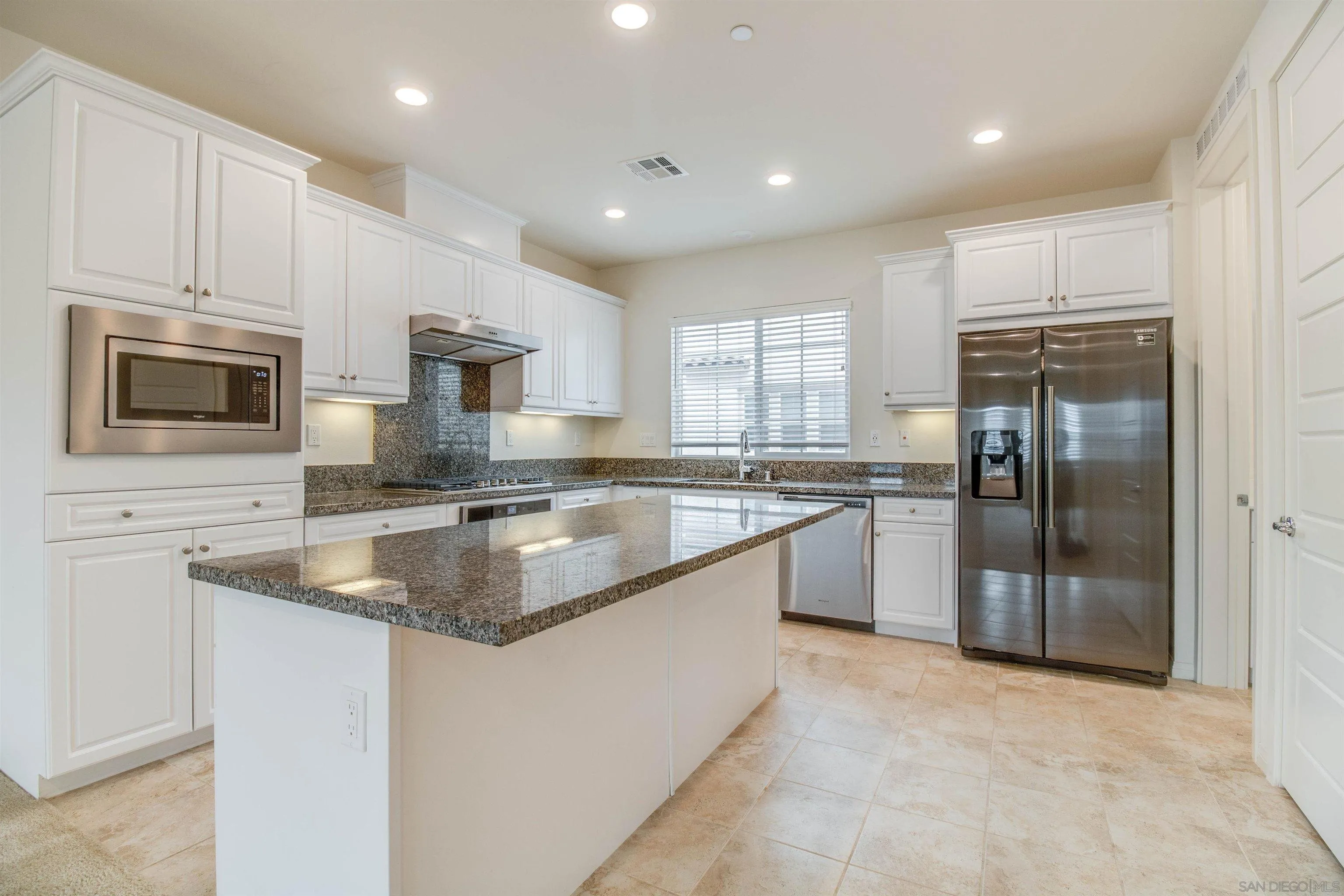 a kitchen with kitchen island granite countertop a sink stainless steel appliances and white cabinets