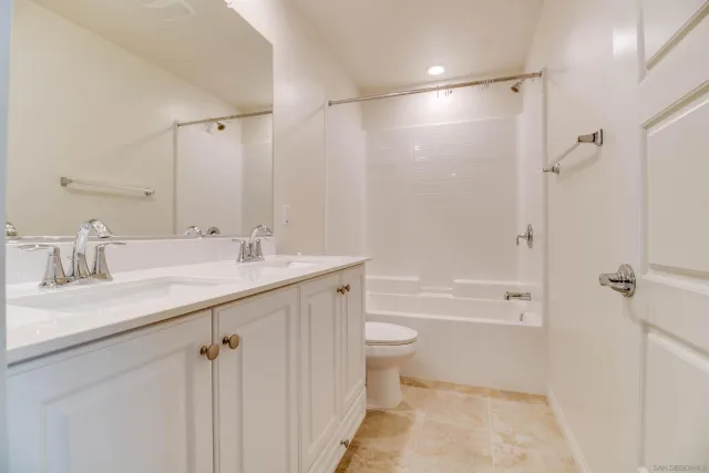 a bathroom with a granite countertop toilet sink and mirror
