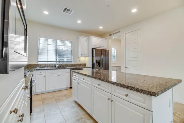 a kitchen with granite countertop cabinets stainless steel appliances a sink and a window