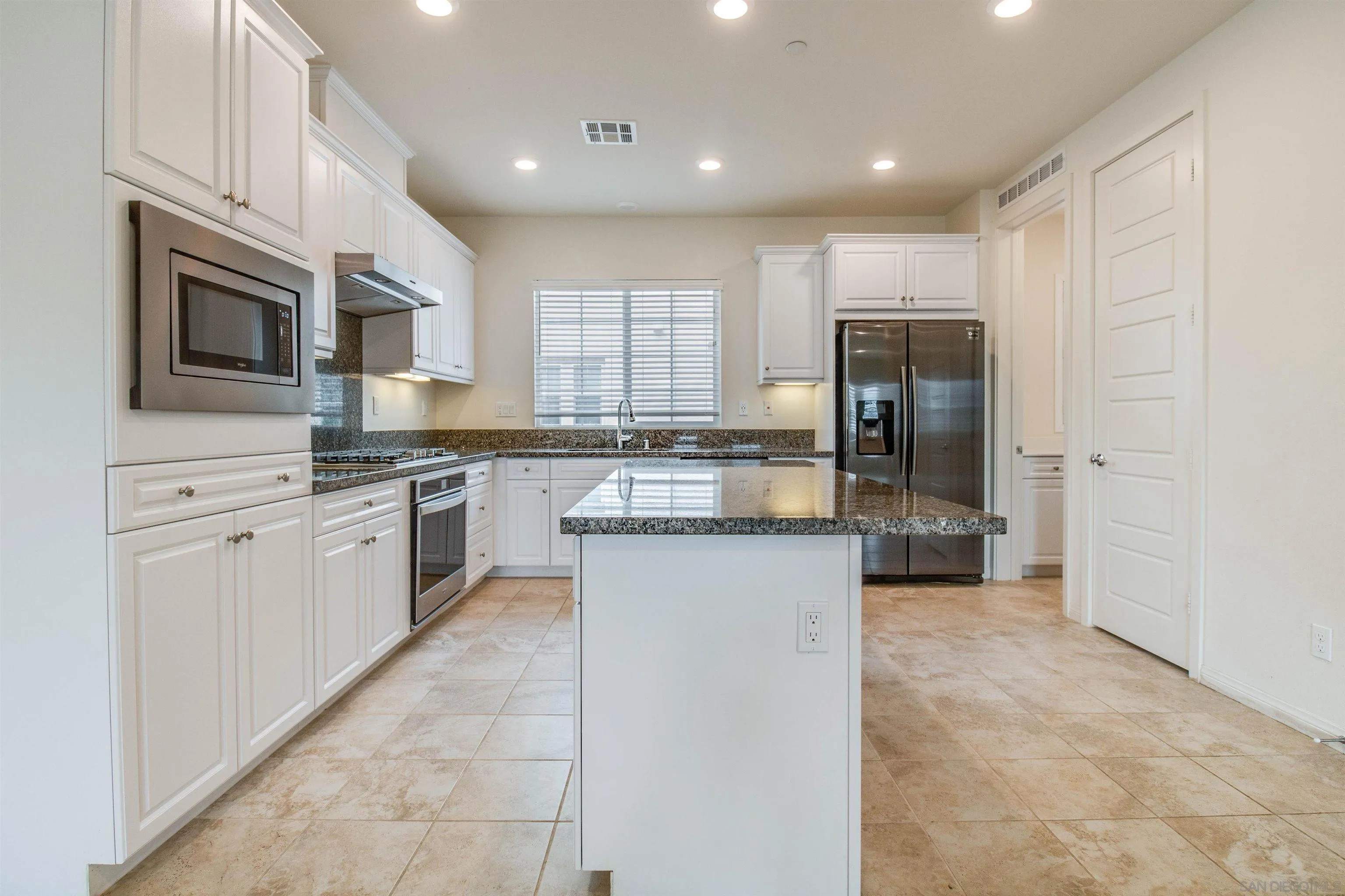 6012 Village Center Loop Road, Unit 35 San Diego, CA 92130 - Photo 25 of 29 a kitchen with white cabinets and stainless steel appliances