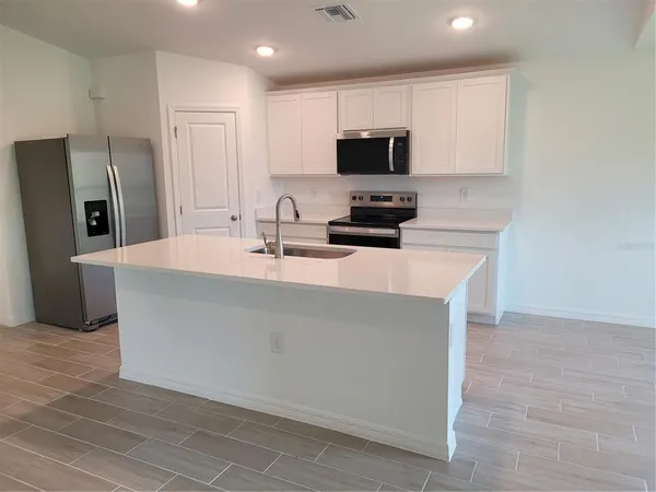 a kitchen with kitchen island a sink appliances and cabinets