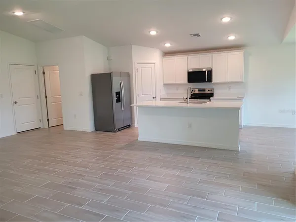 a view of kitchen with stainless steel appliances granite countertop a stove a refrigerator a sink and a refrigerator with wooden floor