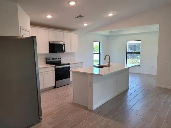 a kitchen with stainless steel appliances a refrigerator a stove a sink a microwave and wooden floor