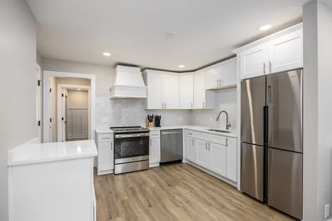 a kitchen with stainless steel appliances granite countertop a refrigerator a stove a sink and a microwave