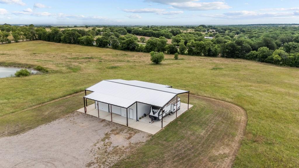 1161 Alsdorf Road Ennis, TX 75119 - Photo 11 of 28 Expansive pole barn with a white metal roof and concrete slab, featuring ample covered parking and a gravel driveway