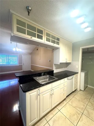 a kitchen with granite countertop a stove and white cabinets