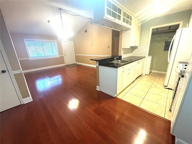 a kitchen with granite countertop a stove a sink and a refrigerator