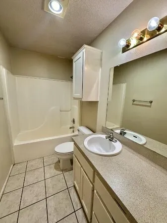 a bathroom with a granite countertop sink a toilet and shower