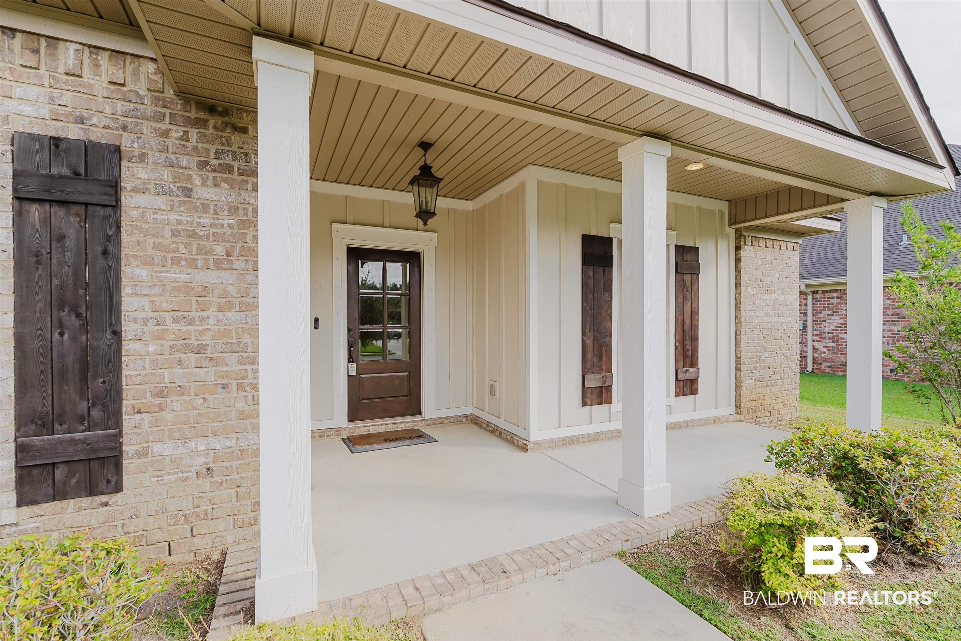 237 Hawthorne Circle Fairhope, AL 36532 - Photo 2 of 14 View of exterior entry featuring board and batten siding, a porch, and brick siding