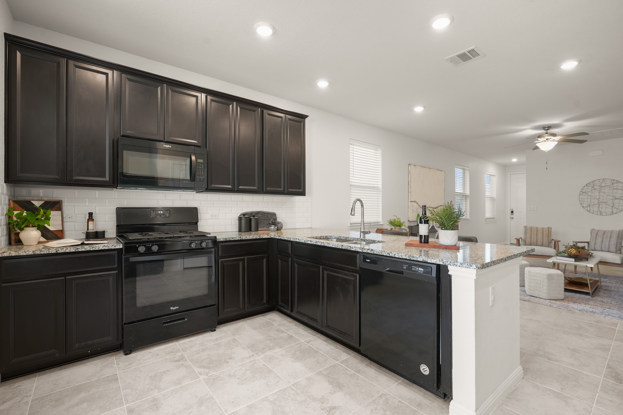 152 Mountain Valley Street Georgetown, TX 78628 - Photo 3 of 38 Dark cabinetry and light stone countertops anchor this modern open-concept kitchen.