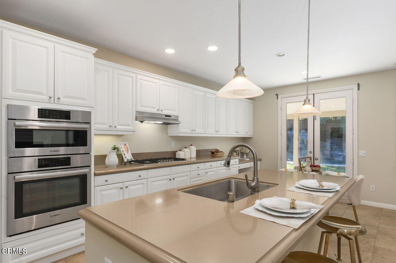 11249 Figtree Terrace Road Corona, CA 92883 - Photo 18 of 53 a kitchen with kitchen island granite countertop a sink a stove and chairs