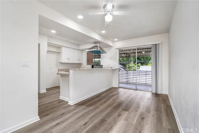 a kitchen with stainless steel appliances granite countertop a refrigerator a sink dishwasher a stove and white countertops with wooden floor