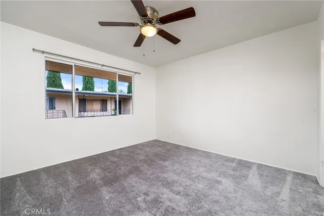 an empty room with window and ceiling fan