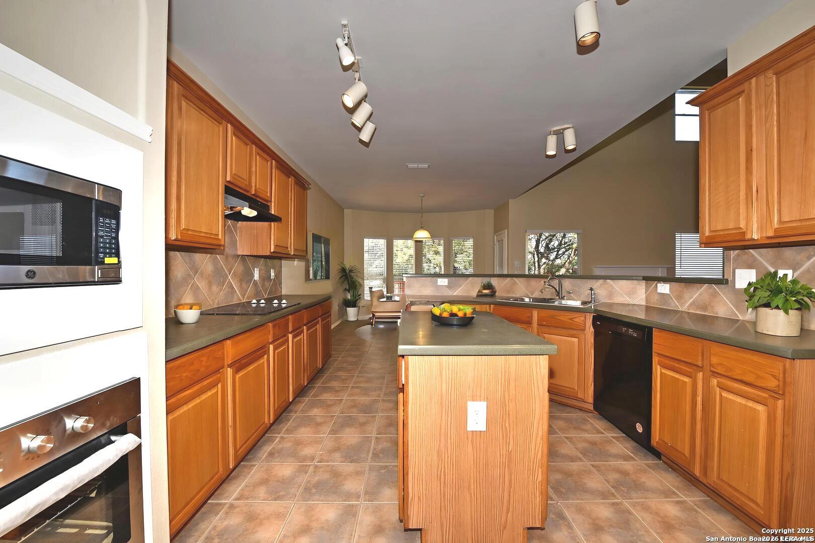 25303 Mesa Ranch San Antonio, TX 78258 - Photo 6 of 54 a kitchen with stainless steel appliances kitchen island granite countertop a stove and a sink