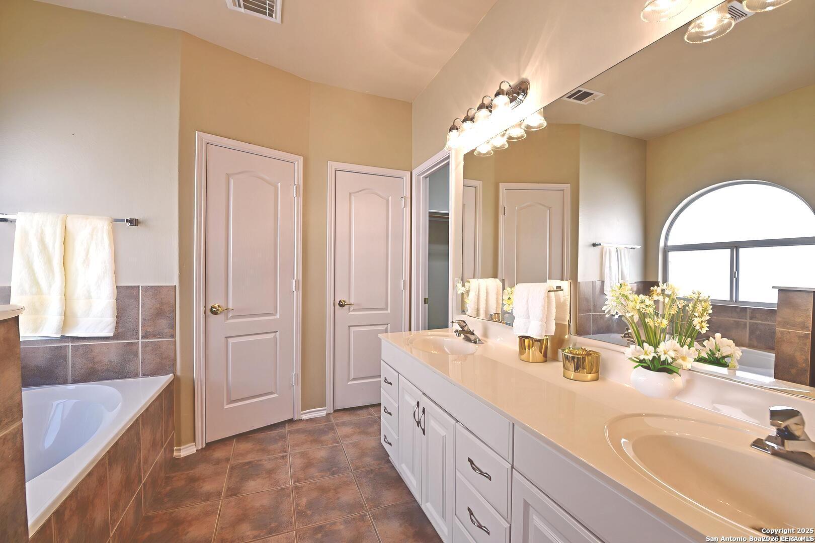 25303 Mesa Ranch San Antonio, TX 78258 - Photo 10 of 54 a spacious bathroom with a double vanity sink a large mirror and a bathtub
