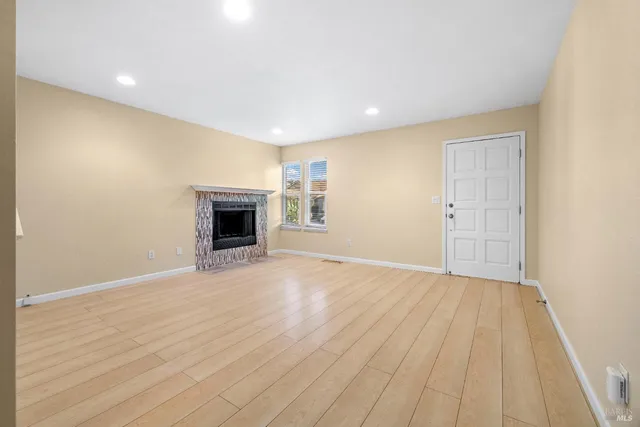 an empty room with wooden floor and fireplace