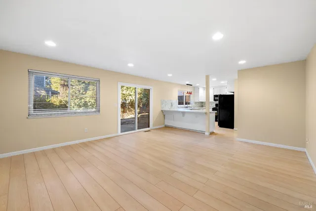 a view of an empty room with a window and wooden floor