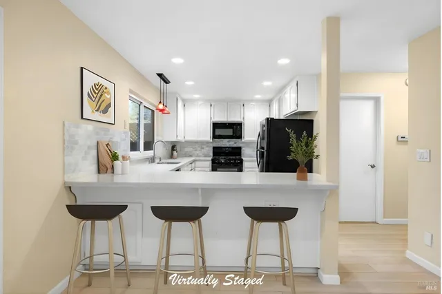 a kitchen with stainless steel appliances granite countertop a dining table chairs and a refrigerator