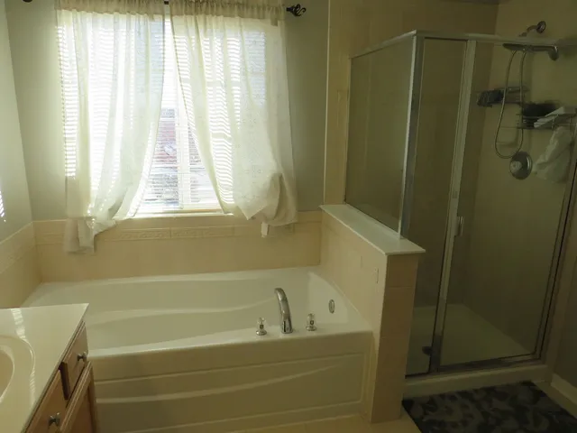 a bathroom with a bathtub a shower and a window
