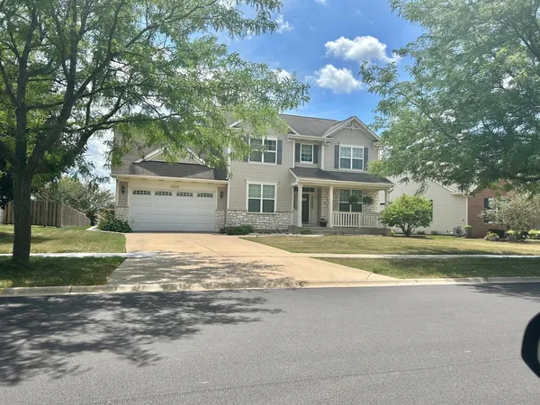 a front view of a house with a garden and trees